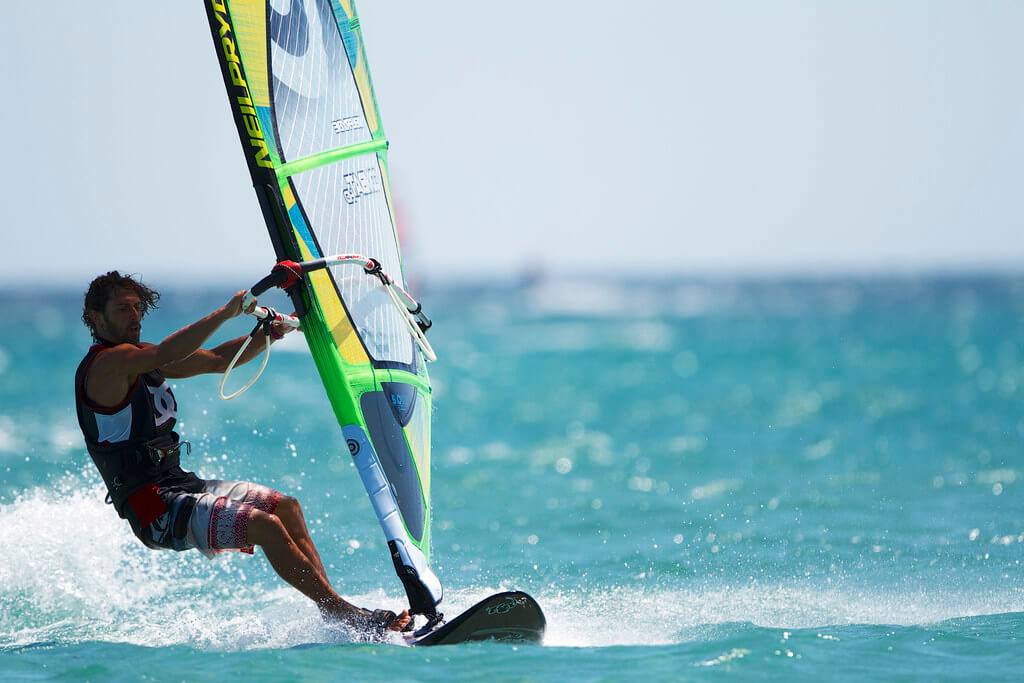 Windsurfer with colorful sail on turquoise sea