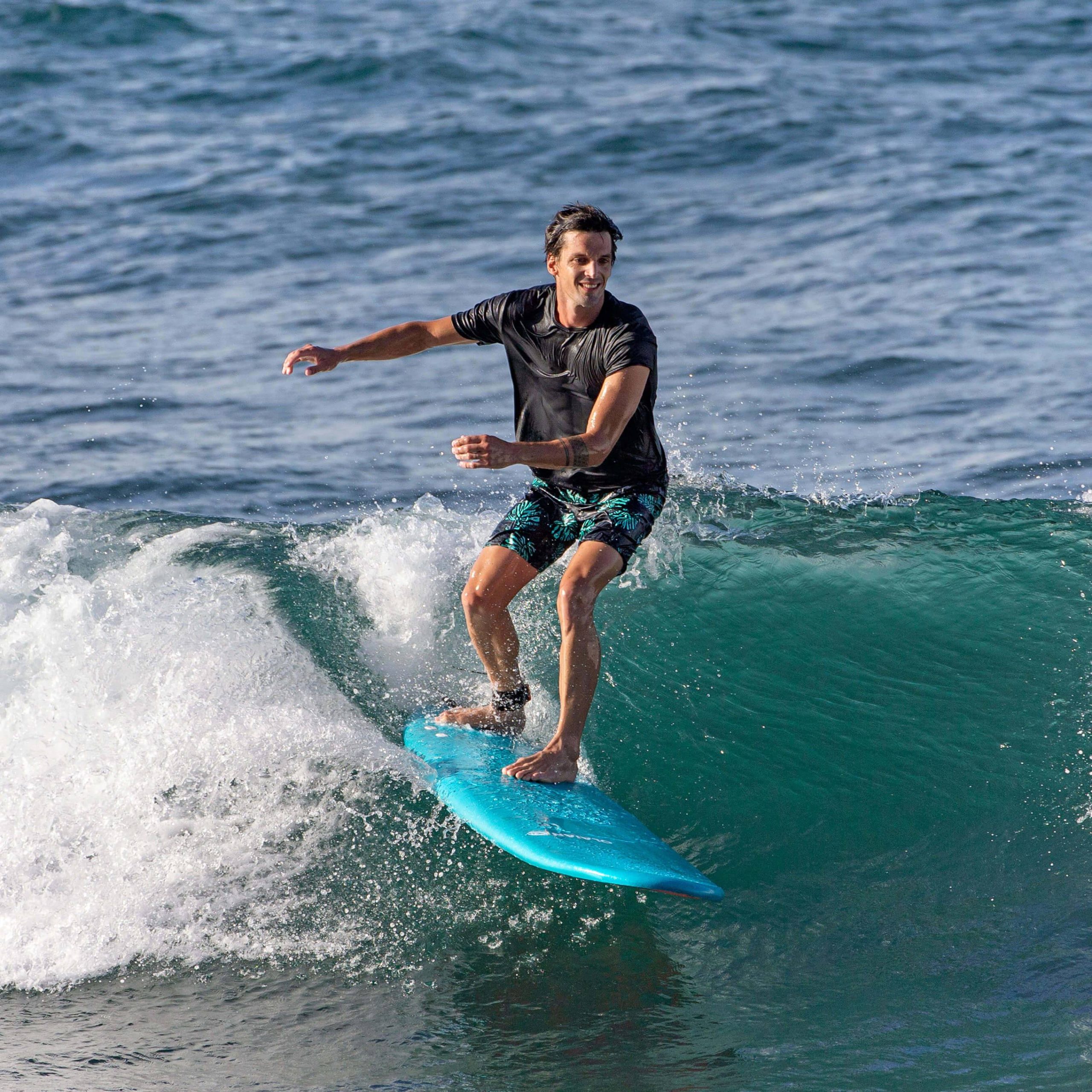 Surfer riding small wave on blue surfboard